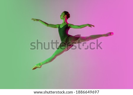 Flying. Young and graceful ballet dancer isolated on gradient pink-green studio background in neon. Art, motion, action, flexibility, inspiration concept. Flexible ballerina, weightless jumps.