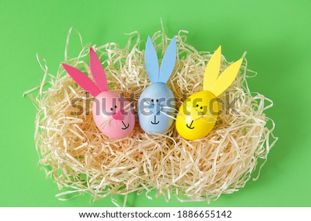 Easter eggs and cute bunny in nest on green background. Festive decoration. Happy Easter.