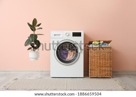 Washing machine and basket with laundry near color wall Royalty-Free Stock Photo #1886659504