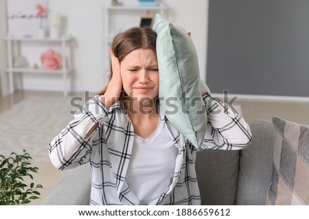 Young woman suffering from loud noise at home Royalty-Free Stock Photo #1886659612