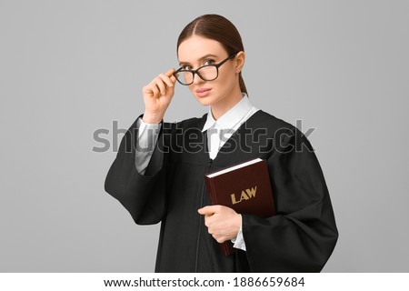 Female judge with book on light background
