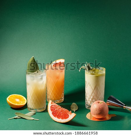 Set of various colorful cocktails over green background. Side view, copy space