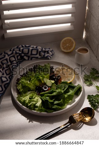 Green vegan salad from green leaves mix and vegetable, on white table. Selective Focus