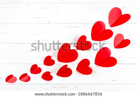 Valentine's card on a white wooden background a lot of red hearts. Ready-made romantic greeting card with copy space. Minimalism concept, declaration of love. Valentine's Day, Mother's Day, Wedding.