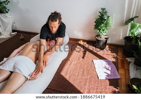 Stock photo of relaxed man enjoying body massage while lying in the floor.