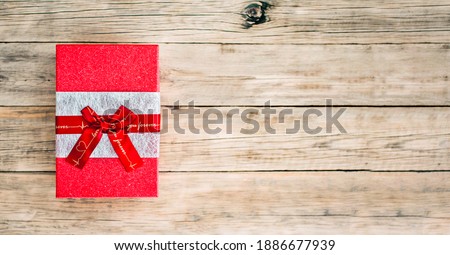 Red gift box with a bow on an old wooden background. Copy space