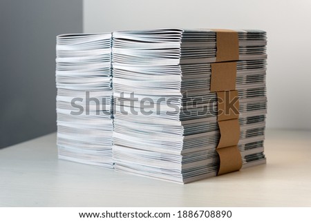 Bundles of newly printed catalogues fastened with brown paper arranged neatly in a stack on a white table Royalty-Free Stock Photo #1886708890