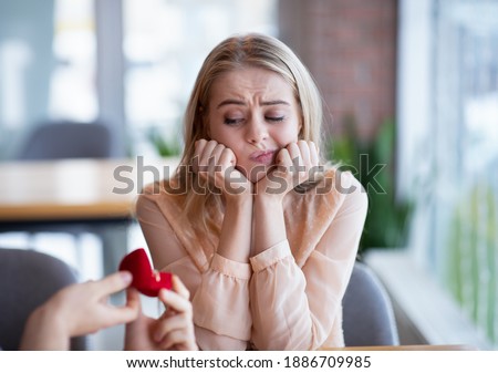 Bored millennial lady not willing to accept engagement ring, rejecting marriage proposal at cafe. Young woman saying NO to her boyfriend, refusing to marry with wrong candidate Royalty-Free Stock Photo #1886709985
