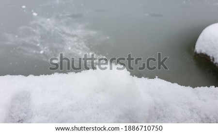 Forozen lake covered with snow in the foreground. Abstract winter photography.