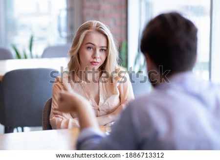 Bad date. Young woman feeling bored during dinner at cafe, unhappy with her boyfriend, disinterested in conversation. Stressed couple having difficulties in relationship, arguing in coffee shop
