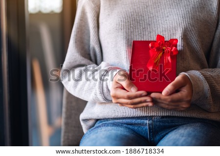 Closeup image of a woman holding a red present box 