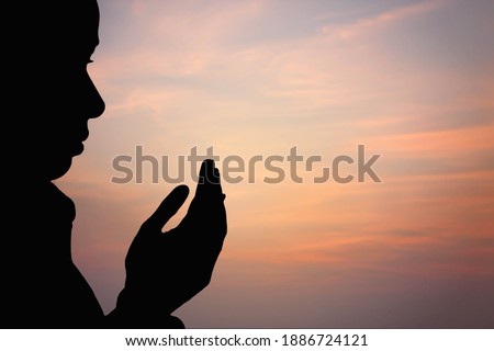 silhouette of muslim woman praying on sky background