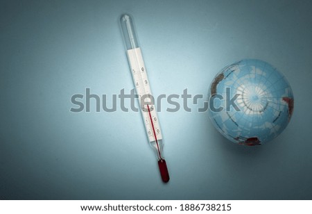 Global warming still life. Globe and thermometer on blue background. Global climate issues. Eco concept