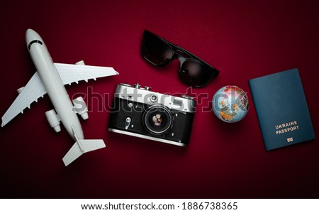 Tourism and travel concept. Globe, passport, passenger plane figurine, sunglasses and camera on red background. Top view. Flat lay