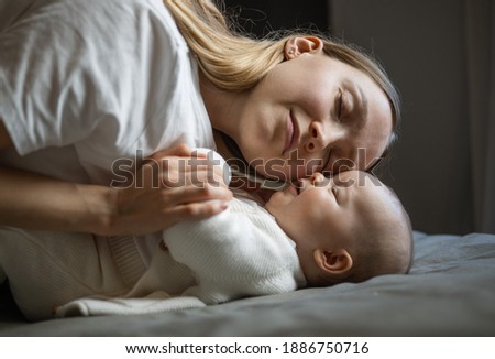 Beautiful mother with her baby. Young beautiful woman looks at her little daughter. Baby girl laughing in her mother's arms.