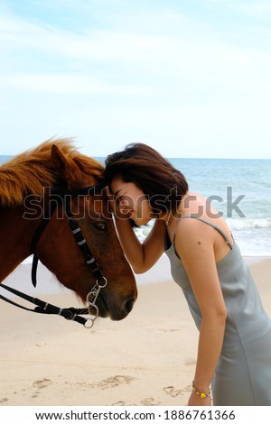 Asian young woman hugging brown horse at Hua Hin beach, Prachuap Khiri Khan, Thailand
