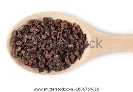 Chopped, grated cocoa pieces in wooden spoon isolated on white background, top view