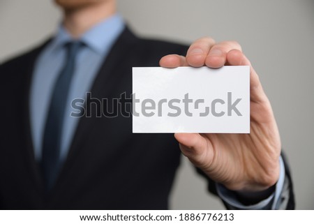 Businessman ,Business Man's hand hold showing business card - close up shot on grey background. Show a blank piece of paper. Paper visit card.