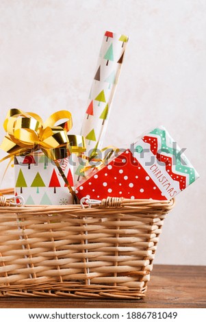 Wrapped Christmas gifts in a storage basket on a brown wooden background. New Year holidays concept.