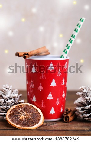 Red cup with hot drink and New Year's decor on a brown wooden background.