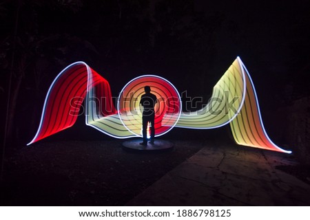 One person standing alone against beautiful red and yellow circle light painting as the backdrop