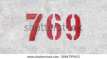Red Number 769 on the white wall. Spray paint.