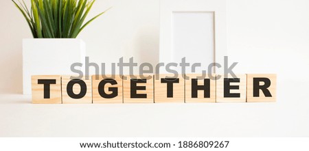 Wooden cubes with letters on a white table. The word is TOGETHER. White background.