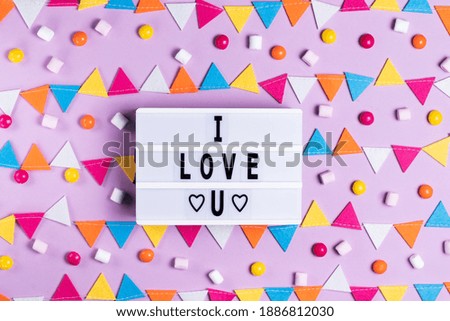 The inscription I love you greeting card for Valentine's Day and Valentine's Day on a white board on a pink background with a multicolored garland holiday