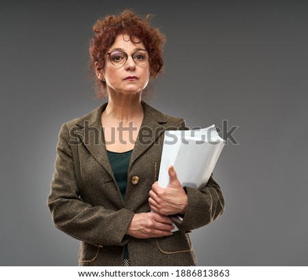 Senior teacher holding exam results with a severe expression