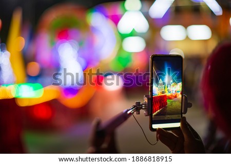 The girl holds her finger in front of the smartphone. against the background of a Christmas tree with festive decor