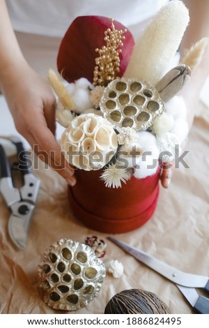 Hands compose the decoration. The are objects on the table. Scissors, vases, and flowers