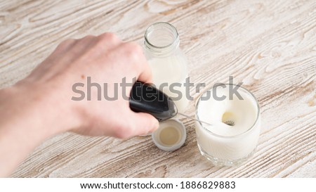 Mixing milk in glass by milk frother. Making foamy milk with frother. Milk handheld mixer. Royalty-Free Stock Photo #1886829883