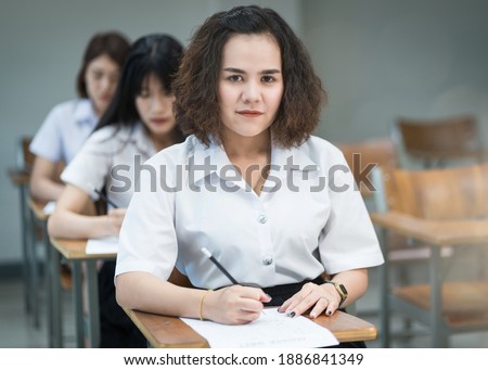 Portrait of cheerful Asian female college students writing and studying in the classroom. Selective fous teenage universty students studying in classroom.