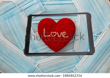Red heart  shape  in tablet with medical mask background.  Concept of  love and healthcare