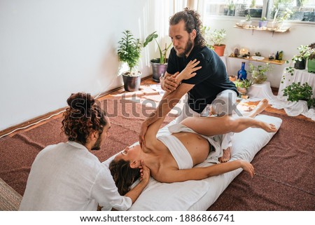 Stock photo of relaxed pregnant woman lying in the floor and receiving body massage with natural oils.