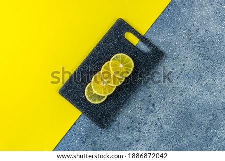 Creative food background of ultimate gray and illuminating trending color. Lemon and cutting board on gray and yellow table surface