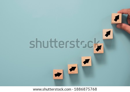 Business investment growth concept , Businessman holding wooden cube block which print screen up and increase black arrow on blue background.