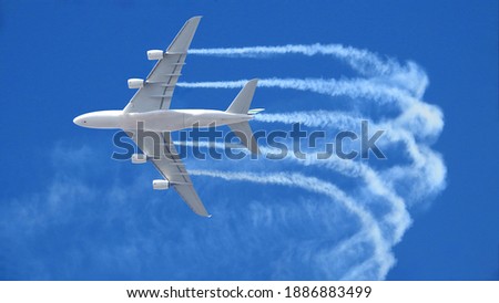 Zoom photo of passenger airplane leaving white smoke trails in deep blue sky while flying at high altitude