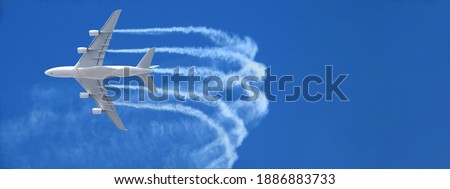 Ultra wide zoom photo of passenger airplane leaving white smoke trails in deep blue sky while flying at high altitude Royalty-Free Stock Photo #1886883733
