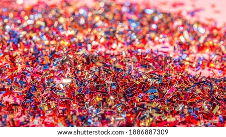 Close-up of a bunch of shiny confetti on pink background. Carnival and party concept. Horizontal photography. Copy Space
