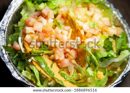 Tacos in a carry out tin with extra shredded lettuce and diced tomatoes