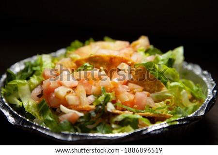 Tacos in a carry out tin with extra shredded lettuce and diced tomatoes