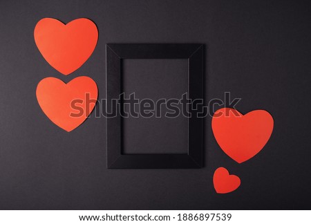 Hearts composition. Photo frame and red hearts on black background. Valentines day concept. Flat lay, top view, copy space