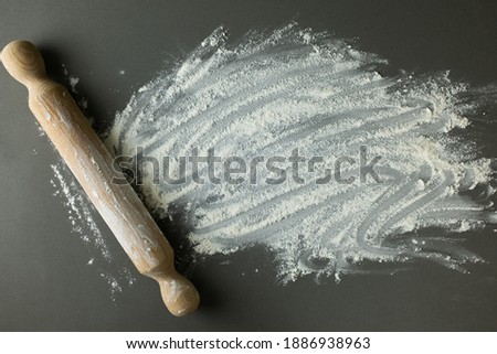 Flour and wooden rolling pin on a gray background, baking ingredients.