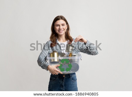 Metal Recycling. Young Smiling Woman Holding Plastic Container Box With Tin Cans, Female Eco Volunteer Enjoying Garbage Recycling And Zero Waste, Standing Over Light Studio Background, Copy Space
