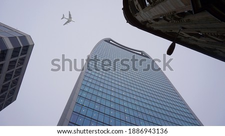 Looking up passing airplane at high altitude above famous Walkie Talkie building facade - London city skyline, financial district, United Kingdom