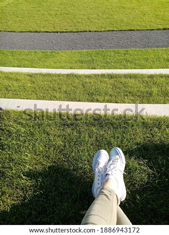 Relaxing mood with crossing legs with white trainers shoes on the fresh cut green grass