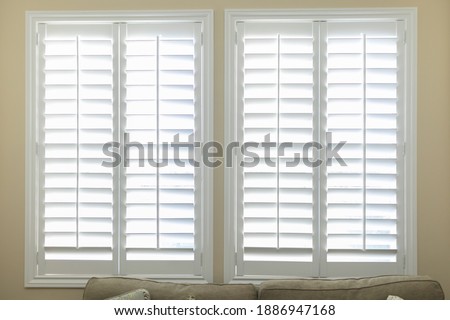 A set of open white plantation shutters in a light butter yelllow room Royalty-Free Stock Photo #1886947168