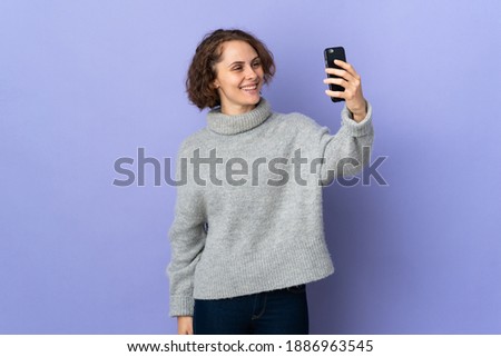 Young English woman isolated on purple background making a selfie