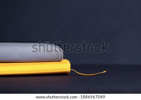 Yellow illuminating notebook with bookmark and grey business card holder on dark grey background. Useful habits concept